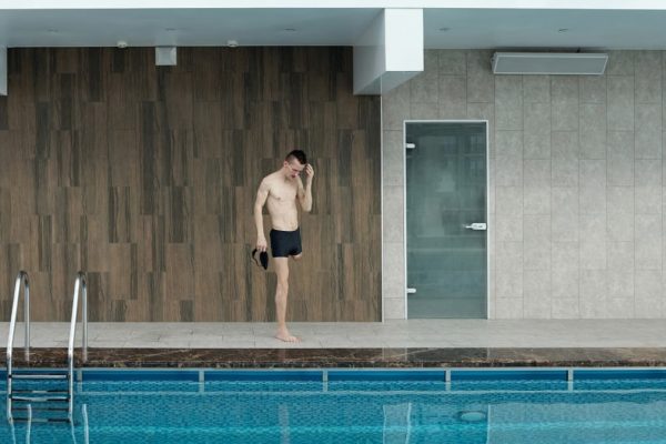 Amputee athlete preparing at an indoor swimming pool, portraying determination and fitness.